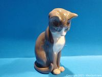 Front and angled view of the glazed ceramic cat figurine showing color, posture, and facial details.