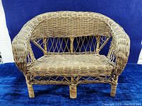Front view of vintage miniature wicker rattan bench chair showing woven seat, curved armrests and crisscross backrest detail.