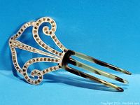 Metal hair comb with rhinestones in scroll design on blue background