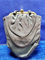 Front view of the black satin evening bag purse showing gathered fabric draping and gold-tone clasp at top