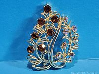Close-up of vintage berry leaf brooch with topaz and aurora borealis rhinestones on gold-tone metal.