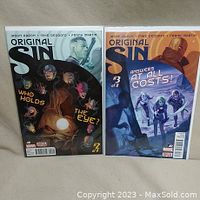 Photo of Original Sin comic books issues #2 and #3 with detailed front covers shown, bagged and boarded condition visible.