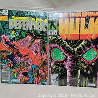 Two comic books displayed side-by-side: The Defenders #98 and The Incredible Hulk #389, both with Man-Thing themes.