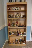 Full front view of maple bookcase fully loaded with trophies and other items for scale and perspective.