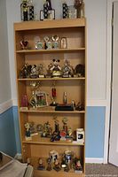 Wooden bookcase with multiple shelves filled with assorted trophies, plaques, and figurines mainly gold-tone with black columns.