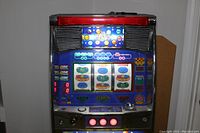 Front view of entire slot machine powered on showing upper display, reels, control panel and lower illuminated ‘BINGO’ signage