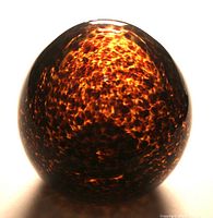 Top view of large glass egg showing deep brown mottling and reflective surface.