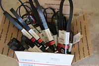 Box containing over 25 new car fan belts by Gates with tags and labels visible