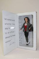Barbie doll in original packaging showing doll with houndstooth jacket, red top, black skirt, white boots, and black handbag.