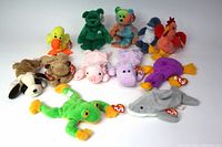 Photo showing all 12 vintage Beanie Babies laid out together, displaying variety of colors and animals including bears, birds, aquatic animals, and more, all with original tags.