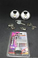 Overall lot showing all locks including two large round padlocks, four smaller locks, and the packaged tow hitch lock.