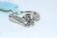 Front angle view of the sterling silver engagement ring highlighting the round cut solitaire and side stones with the split band design.