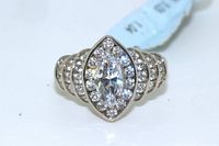 Front view of sterling silver ring showing large marquise cut center simulant diamond surrounded by smaller round simulant diamonds and wide band with multiple rows of simulant diamonds.