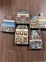Five Brandywine Woodcrafters wooden village buildings grouped on a wooden surface: 5 & 10 Cent Store, Hardware Store, Library, Country School, and Family Practice.