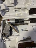 Buffalo pneumatic air chisel tool resting inside Ryobi branded plastic case with two attachments in molded slots.