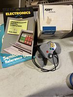 Full view of electronics books stacked with Nintendo 64 controller and Kraft joystick box and joystick