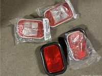 Four back up lamps, two different types, sealed in plastic, one pair with black rubber grommets, another pair with red rims.