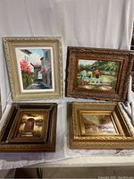 Four paintings displayed together showing different themes and ornate frames