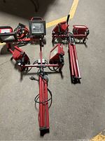Photo showing three red work lights, two mounted on red tripods, arranged on concrete floor.