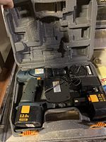 Open carrying case containing Ryobi 12.0V cordless drill with battery, charger, and power cable inside molded compartments.
