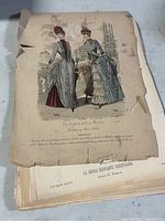 Photo of a hand-colored Victorian fashion print showing two women in period dresses and hats, aged paper with worn edges