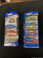 Two unopened Hot Wheels 5-pack toy car packs with colorful die-cast cars visible through clear packaging.