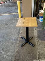 Full view of custom table stand with square plywood top featuring inlays and black cast iron base.