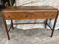 Front view of the entire wooden side table showing two drawers with metal handles and decorative trim.