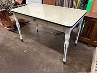 View showing enamelled steel top, white-painted legs with black accents, and drawer face without drawer box.