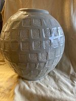 Full front profile of the large celadon green glazed vase showing rounded body and block pattern texture