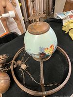Top view of hand-painted glass globe and attached brass crown and cap, showing floral design and patina on brass.