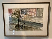 Framed watercolour street scene showing tree planter, two figures, mat and frame