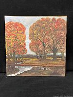 Photo of square oil painting on canvas board showing autumnal landscape with trees and pond, no visible signature.