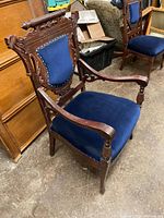 Side angled view showing detailed wood carving, armrest shape, seat upholstery, and overall chair structure.