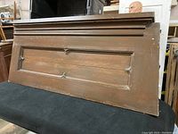 Full view of a dark stained solid oak wood panel with decorative molding and inset recessed panel design.