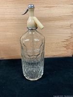Front view of vintage Laurentian Spring Water bottle showing beige siphon mechanism attached to clear glass bottle with embossed branding.