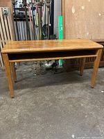 Front view of the vintage solid oak school desk showing rectangular top, four straight legs, and open storage shelf.
