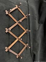 Extended view of the wooden wall-mounted coat rack showing its accordion style and multiple pegs.