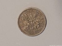 Reverse side of 1962 UK six pence coin showing floral design and year.