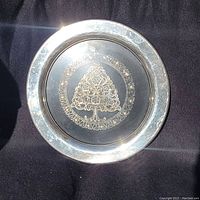 Front view of the aluminum Christmas plate showing the etched carved tree in the center and polished rim.