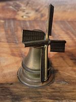 Top-angle image showing the copper windmill figurine with detailed blades and conical base on a wooden surface.
