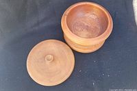 Carved wooden dish with lid placed on black surface, showing the interior and lid.