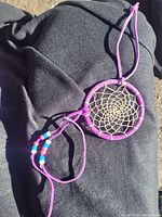 Photo of a vintage hand made dream catcher with purple leather wrapped ring, woven web, and colorful beads on purple straps.