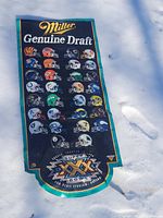 Full view of the large Miller Genuine Draft vinyl football banner laid out on snow showing all NFL helmets and Super Bowl XXX logo.