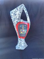 Front view of the uniquely shaped pottery vase with speckled grey-white texture and central red bordered colorful design panel.