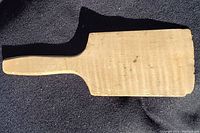 Top and side views of the antique butter paddle made from quilted maple showing grooved rectangular blade and smooth handle.