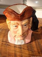 Front view of vintage toby mug showing detailed face of man with brown tri-corner hat and painted facial features.