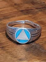 Close-up photo of the men's sterling silver ring showing turquoise inlay with a triangle design and open adjustable band.
