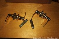 Two brass door handles with locking mechanisms including accompanying lock parts laid out on wooden surface.
