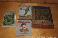 Four Canadian military books on a wooden surface: 'The Oxford Book of Canadian Military Anecdotes', '242 Squadron The Canadians', 'Field Marshal Viscount Montgomery', and 'Holland and the Canadians' spiral-bound.